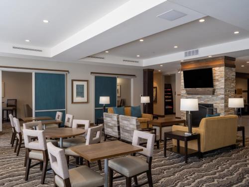 a dining room with tables and chairs and a fireplace at Staybridge Suites - Sioux City Southeast by IHG in Sioux City
