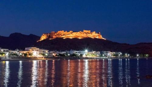 a mountain lit up at night next to a body of water at New Loft by Ossiano Pool Villas, Heating Pool,2 min drive to Haraki Beach & 10 to Lindos in Haraki