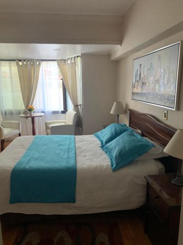 a bedroom with a large bed with a blue blanket at Hotel Marina Azul in Viña del Mar