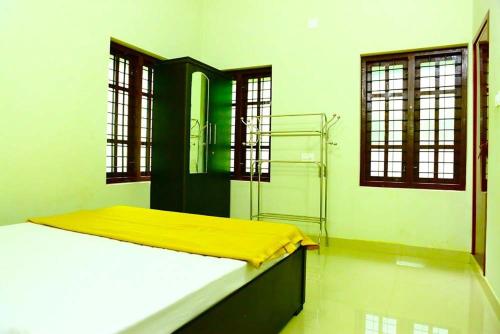 Cette chambre comprend un lit avec une couverture jaune. dans l'établissement Shibi's Tea Garden Heritage, à Vayittiri