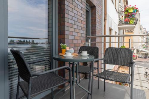 een tafel en stoelen op een balkon met uitzicht bij Przestronny Apartament z Balkonem - Przy Porcie - Świnoujście by Renters in Świnoujście