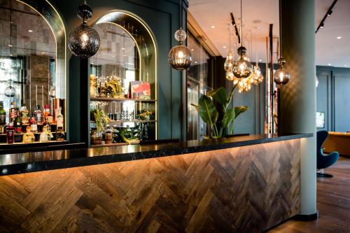 a bar with a wooden counter with pendant lights at Motel One Graz in Graz
