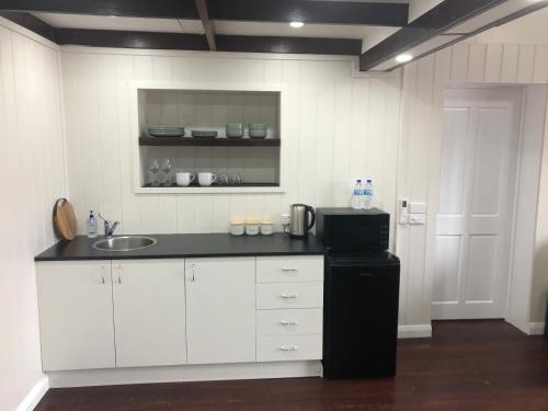a white kitchen with a sink and a refrigerator at Toodyay Manor in Toodyay