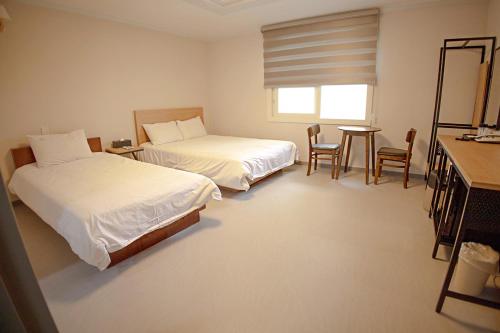 a hotel room with two beds and a table and chairs at Trevi Hotel in Jeju