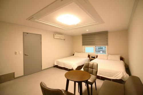 Habitación de hotel con 2 camas, mesa y sillas en Trevi Hotel, en Jeju
