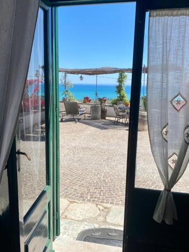 an open door to a patio with a view of the ocean at Villa in Gargano - VILLA BASSO in Monte SantʼAngelo