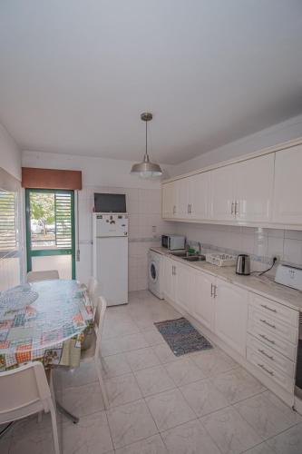 a kitchen with white cabinets and a table in it at Charming Private Rooms in an Apartment A1 Penha - Faro in Faro