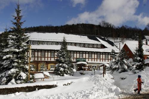 a building covered in snow with a person in front of it at Wanderhotel Sonnebergbaude in Waltersdorf