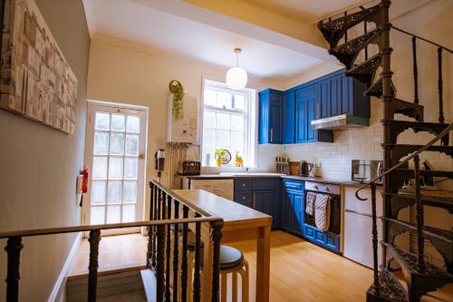 a kitchen with blue cabinets and a spiral staircase at Entire character property in heart of Norwich in Norwich