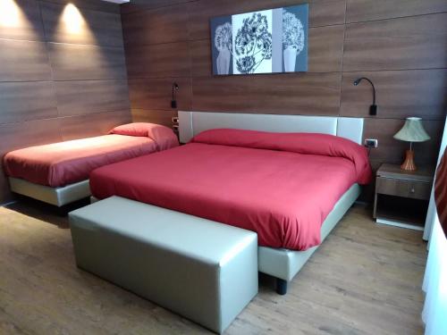 1 dormitorio con 2 camas con sábanas rojas y taburete en Family Center Hotel, en Polla