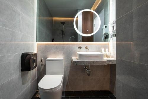 a bathroom with a toilet and a sink and a mirror at Botanic Service Room at Impact Muangthongthani - SHA Certified in Nonthaburi