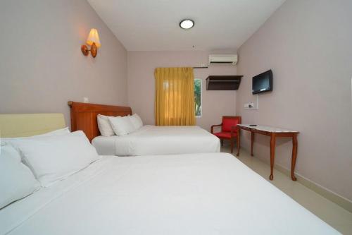 1 dormitorio con 2 camas, mesa y TV en Mila Motel 2 en Pantai Cenang