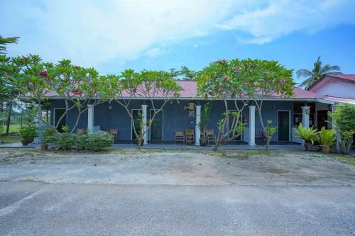 a blue house with trees in front of it at Mila Motel 2 in Pantai Cenang