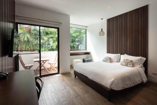 暖武里府Botanic Service Room at Impact Muangthongthani - SHA Certified的一间卧室配有一张床铺和一张桌子,并设有一个阳台