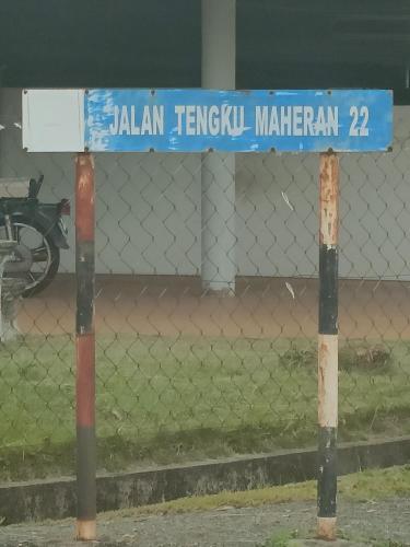 a blue street sign on two poles next to a fence at Adempuri homestay in Jitra