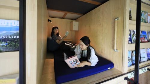 two girls sitting on a couch reading a book at Yutorelo Nikko in Nikko