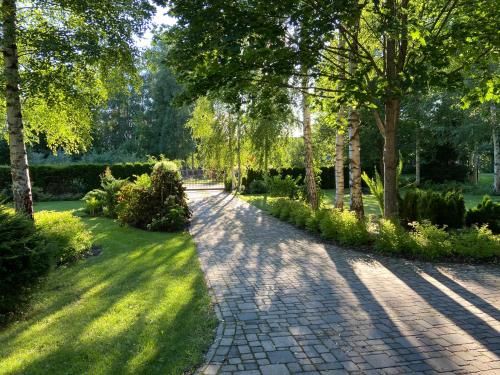 a brick path in a park with trees and grass at Romantic cozy house Kirzacinas pirts with sauna close to seaside in Skulte