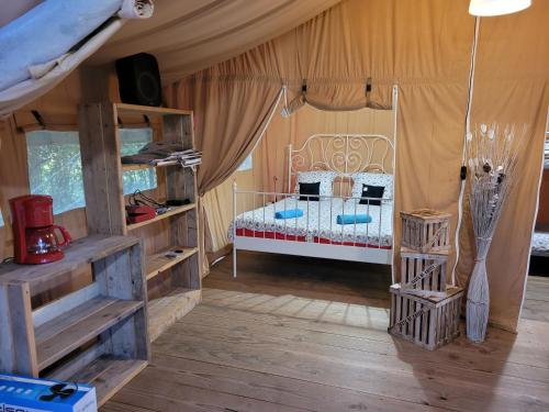ein Schlafzimmer mit einem Bett in einem Zelt in der Unterkunft Tente Lodge Safari in Saint-Martin-des-Besaces
