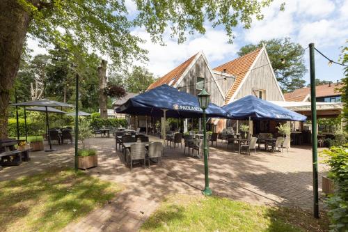 a patio with tables and chairs and blue umbrellas at Hotel Erve Hulsbeek in Oldenzaal