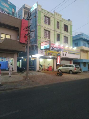 a street with a building and a car parked in front at New City Tower Residency in Tiruchchendūr