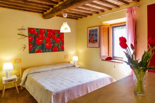 ein Schlafzimmer mit einem Bett und einer Vase aus roten Blumen in der Unterkunft Quercia Grossa in Roccastrada