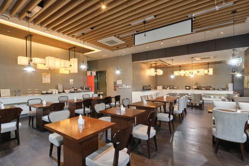Jeju Central City Hotel في جيجو: مطعم بطاولات وكراسي خشبية وبار