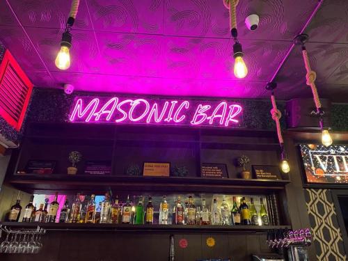 a neon sign above a bar with bottles of alcohol at Masonic Hotel in Waitara