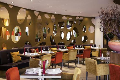a restaurant with tables and chairs and mirrors at Mercure Hotel Groningen Martiniplaza in Groningen