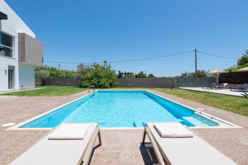 a swimming pool with two chaise lounges next to a house at Marane Deluxe House in Ialyssos