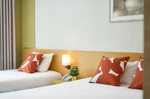 a hotel room with two beds with red and white pillows at Jeju Central City Hotel in Jeju