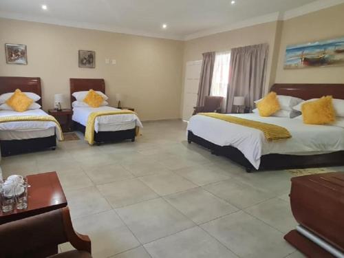 a hotel room with two beds with yellow pillows at Benoni N12 Hotel in Benoni