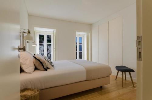 1 dormitorio blanco con 1 cama y 1 silla en Casas d'Mouraria, en Lisboa