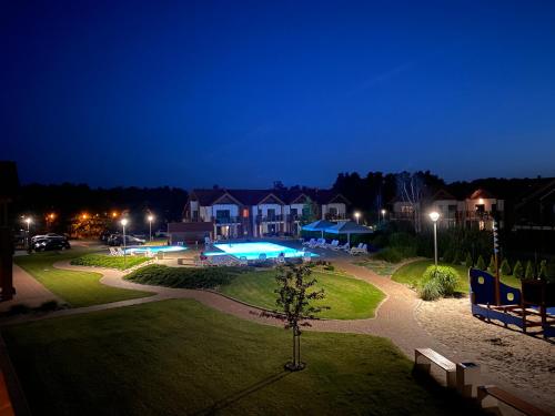a park at night with a house and a swimming pool at Apartament Łebska Ostoja in Żarnowska