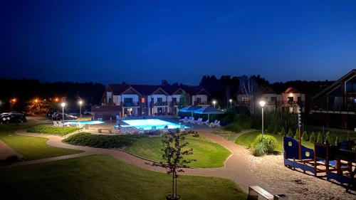 a night view of a resort with a swimming pool at Apartament Łebska Ostoja in Żarnowska