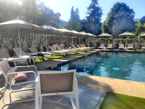 a swimming pool with lounge chairs and umbrellas at Hotel La Fontana in Stresa