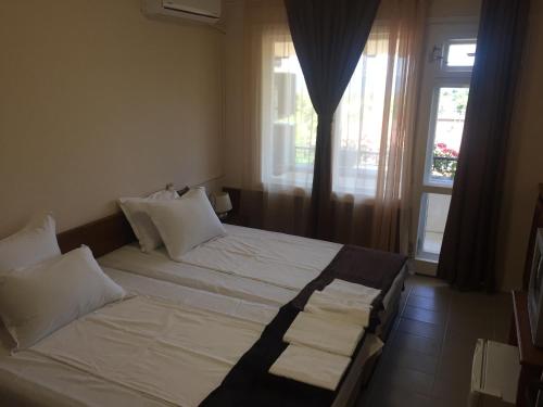 - une chambre avec un lit doté de draps blancs et une fenêtre dans l'établissement Guest House ,,Emotion'', à Balchik