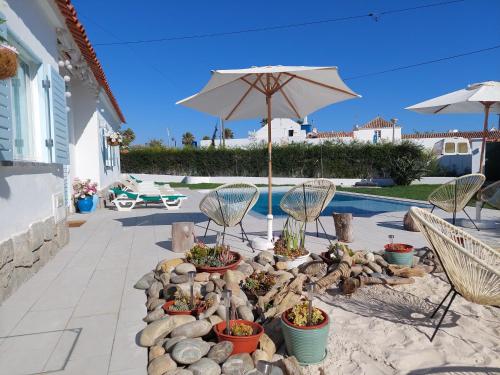 a patio with a table and chairs and an umbrella at Villa Mariana Piscina Privada in Porto Covo