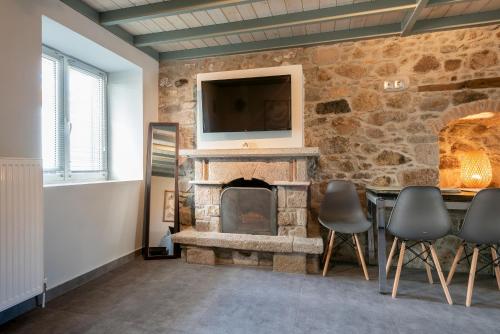 a living room with a stone fireplace and a television at Traditional Stone House in Thános