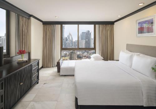 a hotel room with two beds and a large window at Grand President Bangkok in Bangkok