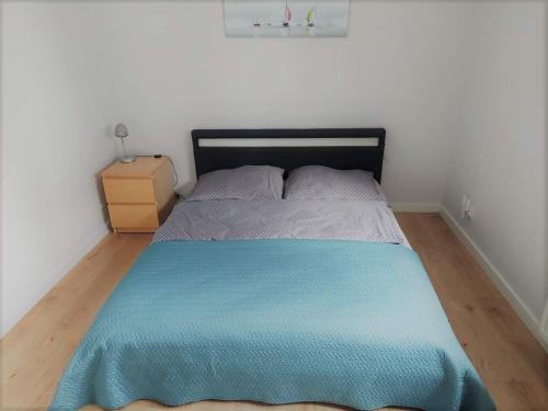 a bedroom with a bed with a blue blanket on it at Apartament Reda z prywatną sauną in Reda