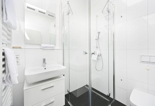 een witte badkamer met een wastafel en een douche bij Ferienwohnung Kala in Juliusruh