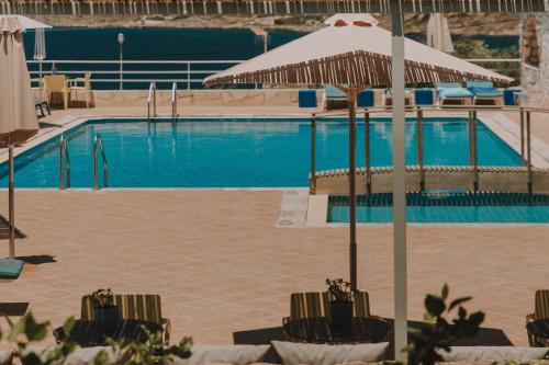 a swimming pool with chairs and an umbrella at Creta Vitalis in Kalathas