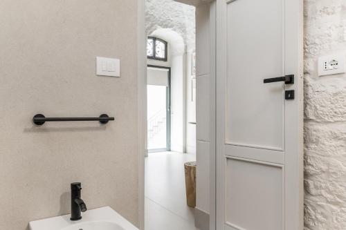 a bathroom with a white sink and a door at Petragrigia Vacation Suite in Ostuni