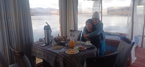 two women standing at a table with a table with a view of water at TITICACA JALTAWI LODGE in Puno