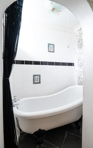 a white tub in a bathroom with a black shower curtain at Enchanted Manor in Niton