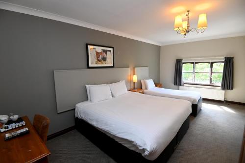 a hotel room with two beds and a desk and a window at Admiral's Table, Bridgwater by Marston's Inns in Bridgwater