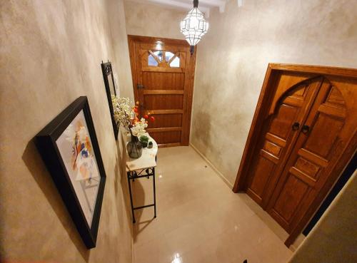 a hallway with a wooden door and a table with flowers at Dar Malika in El Jadida