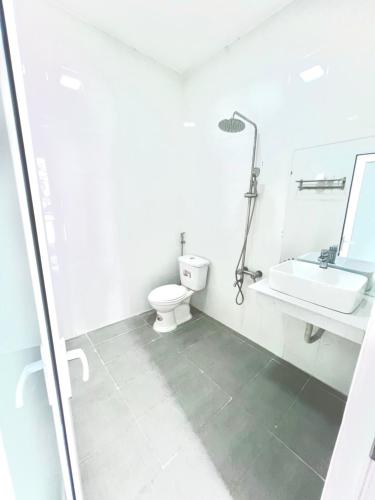 a white bathroom with a toilet and a sink at D'Villa Hotel - Homestay in Kon Tum