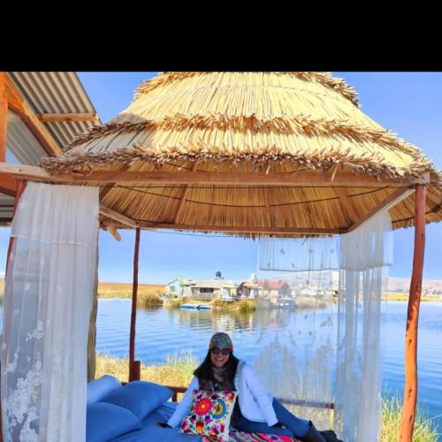a woman sitting on a bed under a straw umbrella at TITICACA JALTAWI LODGE in Puno