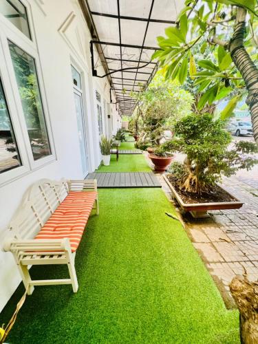 a garden with a bench on a green lawn at D'Villa Hotel - Homestay in Kon Tum